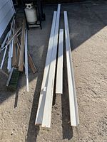 Baseboard, quarter round, and casing trim pieces laid out on pavement, showing length and paint condition.