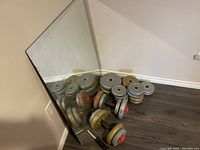 Angle showing mirror resting against wall with weights stacked nearby.