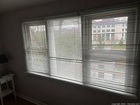 Wide view of four-panel window fitted with horizontal metal blinds showing natural light filtering through the slats.