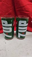Photo showing both 7UP glasses side by side with clear view of logo and green background