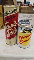 Full view of both vintage tins side by side on a table showing labels and physical condition