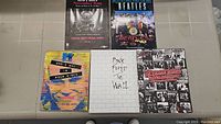 All five rock books arranged on a grey table: G n' Roses, The Beatles, Pink Floyd The Wall, The Rolling Stones, and MTV Who's Who in Rock Video.
