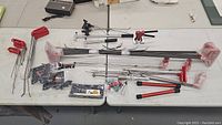 Full view of various dent pulling rods, clamps, and other accessory tools laid out on a table
