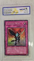 Front view of 2003 Upper Deck Yu-Gi-Oh Gryphon Wing Trap Card graded 10 GEM-MT by WCG in protective casing.