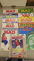 Top-down photo of all 11 Mad Magazines laid out on a table showing colorful various covers and logos spanning the 1970s and 1980s.