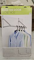 Box front displaying the assembled closet rod holding four shirts on hangers. Shows design and usage.