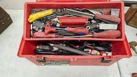 Top view of the toolbox showing screwdrivers, pliers, utility knives, files, and socket wrench in compartments.