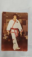 Full body view of Elvis Presley in white karate uniform with red belt.