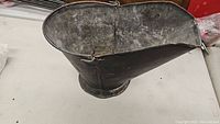 Vintage metal coal bucket viewed from above, showing wide oval top and worn interior.