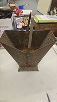 Front view of vintage metal coal bucket showing rust and handle.
