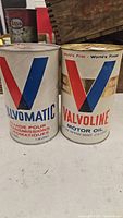 Two vintage unopened Valvoline metal cans: one Valvomatic transmission fluid and one motor oil.