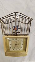 Full view of the vintage Florn bird song alarm clock showing metal birdcage, bird figurine, clock face and base.