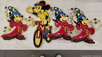 Four vintage plastic Mickey Mouse decorations, including three in red wizard robes and blue starry hats, and one riding a red bicycle in yellow shirt and red hat