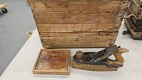 Photo showing the large vintage wooden crate with visible wood grain and patina along with the hand planer and Kleanbore branded wooden box.