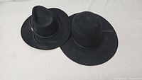 Two black vintage western hats side-by-side showing size and style differences
