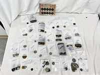 36 plastic bags labeled with country names containing diverse coins from around the world laid out on a white surface