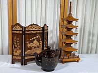 Lot overview showing carved wood pagoda, three-panel crane design screen, and dark brown floral teapot.