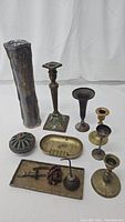 Full view of all assorted vintage brass décor items including several candle holders and decorative trays, showing patina and vintage condition.