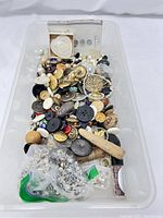 Bin filled with assorted vintage buttons and sewing accessories, showing variety of materials, sizes and colors.