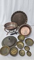 Full view of all the antique brass and copper kitchen items arranged showing the variety of pans, bowls and stands