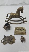 Top view of all five brass figurines: rocking horse, elephant, box, turtle, bell