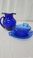 Photo shows the cobalt blue glass pitcher alongside the octagonal platter and matching bowl with handle accents.