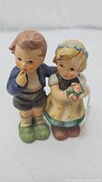 Front view of the Hummel figurine 'We Congratulate' showing boy and girl with flowers