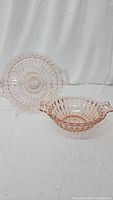 Photo showing pink Depression glass serving bowl and platter, both with handles, styled in Diamond Windsor pattern; platter leaning against backdrop, bowl in front