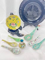 Overall shot of the 9 items including plates, spoons, shoe-shaped vase, and small floral vase.