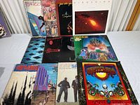 12 vinyl albums laid out on a table showing front covers with visible wear and varied artistic designs