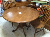 Front view of the round wood dining table with one chair pushed in to side.