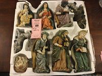 Full view of 9-piece nativity porcelain set in styrofoam packaging showing all figures arranged separately.