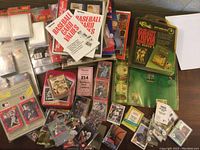 Wide view showing assortment of baseball card packs, baseball trading card games, value booklets, and loose cards on table.