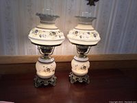 Pair of blue floral 3-way glass hurricane lamps side by side on wooden surface