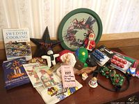 Wide shot of lot showing cookbook, wooden star, figurines, dish towels, small ornaments and holiday decorations