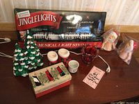 Boxed Jingle Lights, ceramic Christmas tree candle holders, Santa boot votives, red glass votive, ribbon box, two Santa figurines