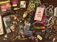 Overview photo of the jewelry lot showing various beaded necklaces, pins, earrings, bracelet, clasps, and a pendant.