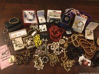 Wide view of assorted costume jewelry including necklaces, rings, brooches, and earrings laid out on a wooden surface