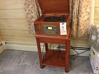 Full view of Crosley multi-player sitting on wooden LP table with storage for records.
