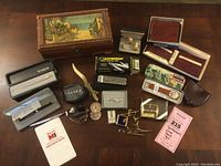 Full overview of all items laid out on table, showing the box, pens, watch, sunglasses, multitool, pocket protector, and various small accessories.