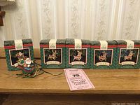 Five Hallmark Keepsake boxes and one Santa Claus in sleigh ornament on a wooden surface.