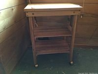 Front and side view of the wooden kitchen cart with cutting board top and two slatted shelves.
