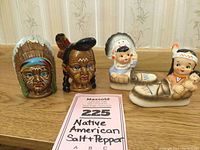 Front view of two salt and pepper shaker sets depicting Native American figures with traditional headdresses on a wooden surface against a wallpaper background.