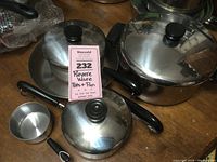 Photo showing the assortment of Revere Ware pots and pans including large pot, saucepan, and lids with black plastic knobs.