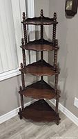 Full view of antique 5 tier corner shelf with turned spindle legs and scalloped shelves