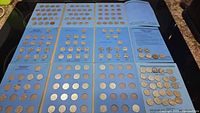 Top view of three open blue albums filled with Canadian nickels from different years and kings.