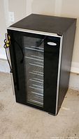 Closed Haier wine cooler fridge with glass front door showing black finish and silver trim