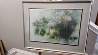 Framed watercolour botanical painting with white flowers and green leaves, showing overall piece hung on wall.