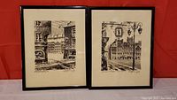Pair of framed city scene watercolour paintings in monochrome, side by side on red background