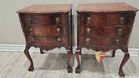 Front view of both bedside tables showing pair, serpentine drawer fronts and carved aprons.